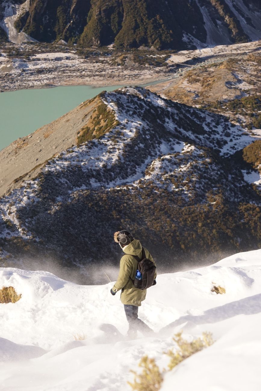 Hiker on New Zealand mountain trail overlooking valley